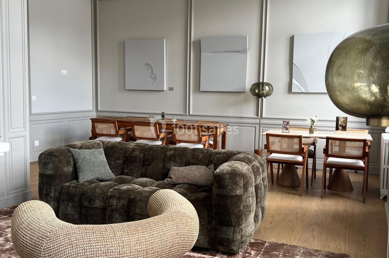 Salon élégant avec fauteuils rembourrés, tapis texturé, table à manger en bois et décorations murales modernes.