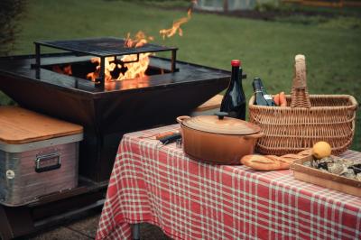 Deux personnes cuisinent des légumes colorés sur une grande plancha en extérieur, par une journée ensoleillée.