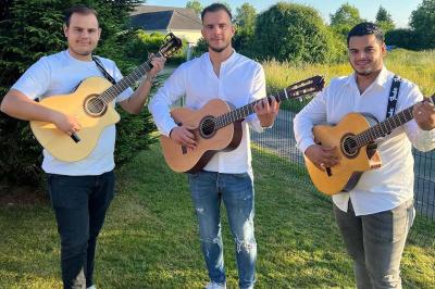 Miniature DJ Le Petit-Quevilly (Seine-Maritime) - Les Gipsy Noy’s #3 Trois hommes jouent de la guitare acoustique dans un jardin, vêtus de chemises blanches et entourés de verdure.
