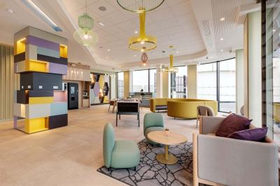 Salle de bain moderne avec douche à l'italienne, lavabo avec miroir éclairé et serviettes pliées sur une étagère.