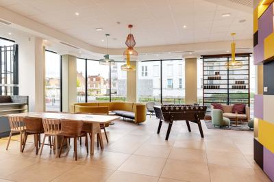 Salle de bain moderne avec douche à l'italienne, lavabo avec miroir éclairé et serviettes pliées sur une étagère.