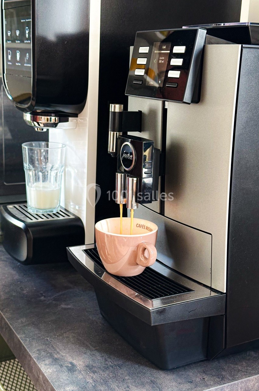 Machine à café automatique versant un expresso dans une tasse beige posée sur son plateau.
