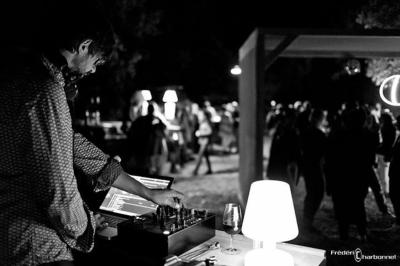 Terrasse couverte avec piste de danse, tables hautes, décoration lumineuse et équipement de DJ au premier plan.