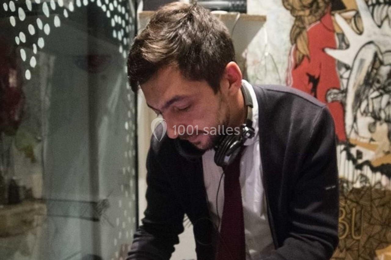 Un homme portant un casque audio autour du cou travaille, entouré de décorations murales artistiques.