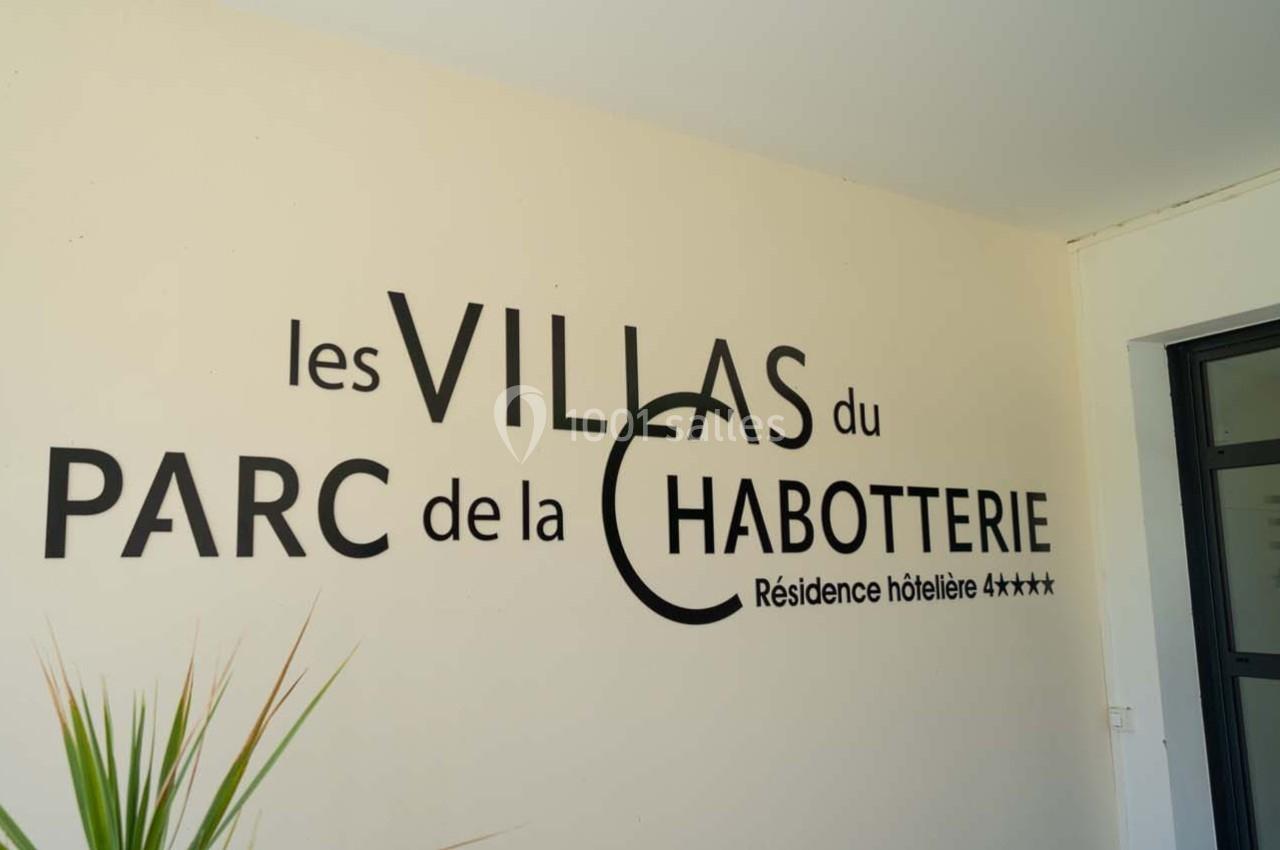 Texte ’Les Villas du Parc de la Chabotterie - Résidence hôtelière 4 étoiles’ sur un mur clair près d'une plante.