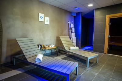 Miniature Location salle Montréverd (Vendée) - Les Villas du Parc de la Chabotterie #22 Deux chaises longues en métal avec serviettes roulées dans un espace spa, près d'un sauna en bois.