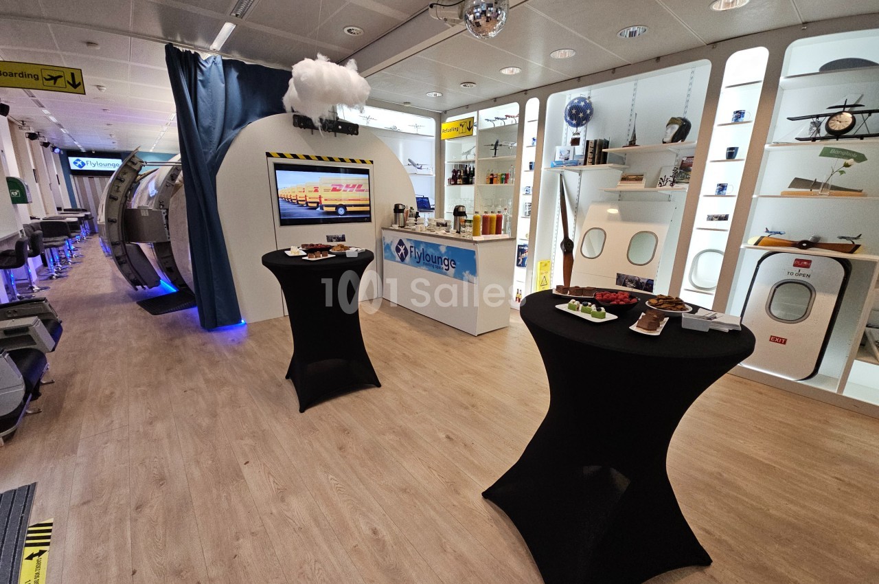 Salle aménagée sur le thème de l'aviation avec tables hautes, vitrines d'exposition et décorations aéronautiques.