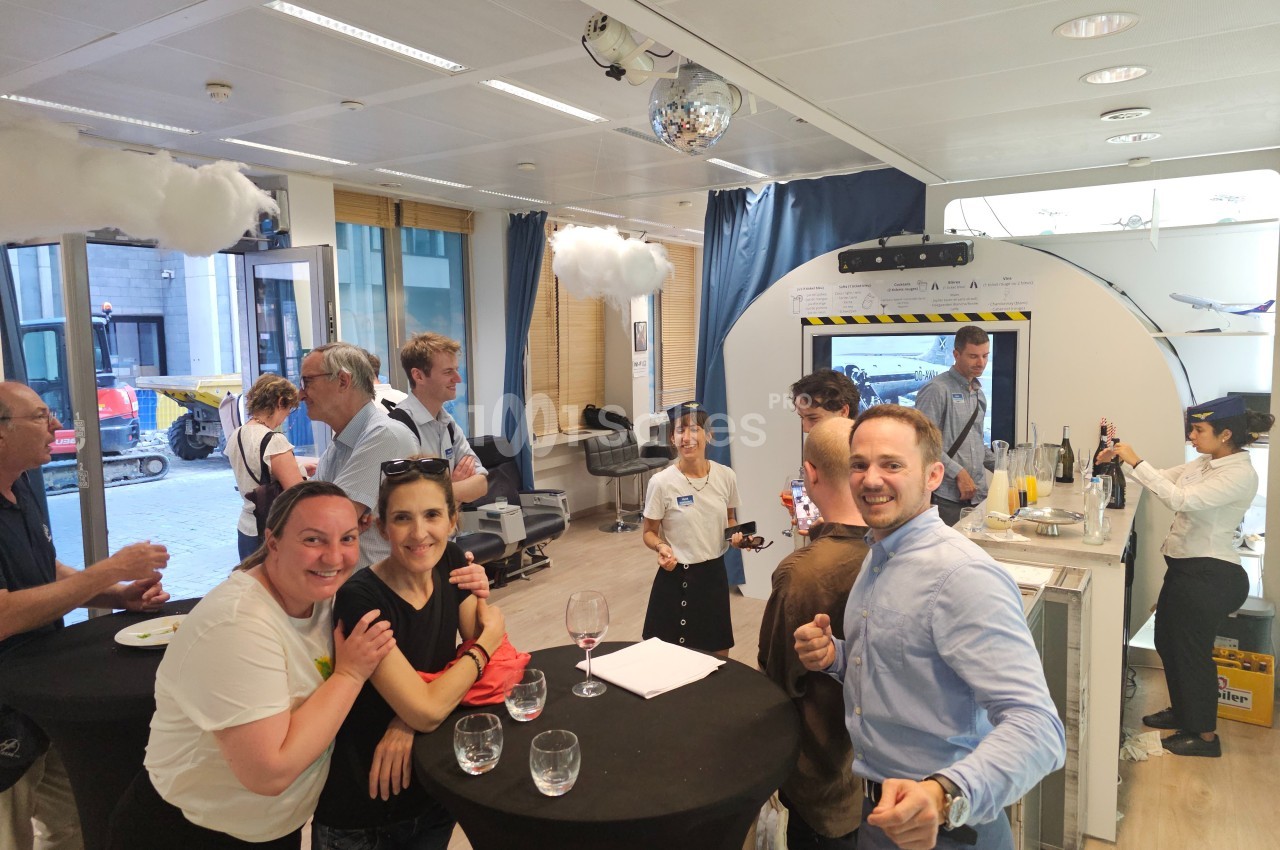 Des personnes discutent et partagent un moment convivial autour de tables hautes dans un espace lumineux.