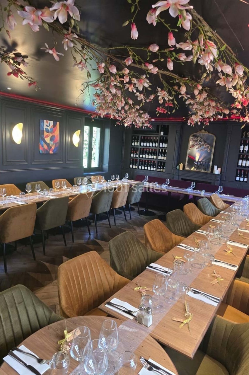 Salle de restaurant élégante avec tables dressées, chaises colorées et plafond décoré de branches fleuries.