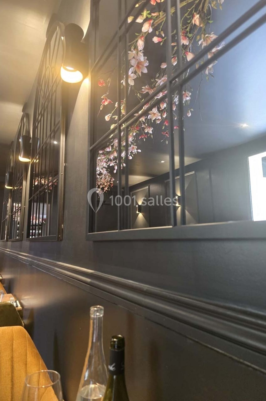 Miroirs encadrés reflétant des fleurs suspendues dans un intérieur sombre et élégant avec des murs gris.