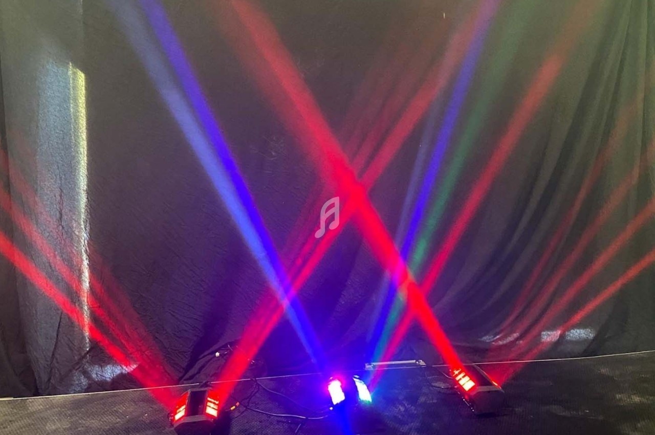 Projecteurs lumineux diffusant des faisceaux rouges, bleus et verts croisés sur un fond sombre.