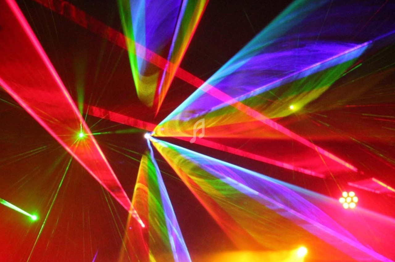 Des faisceaux lumineux multicolores se croisent dans un espace sombre, créant un effet visuel dynamique.