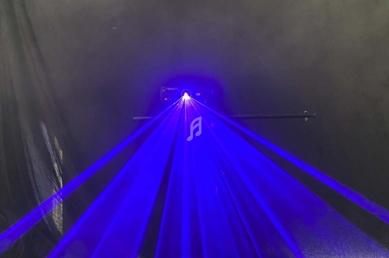 Rayons laser bleus émanant d'un appareil dans un environnement sombre avec un fond noir.