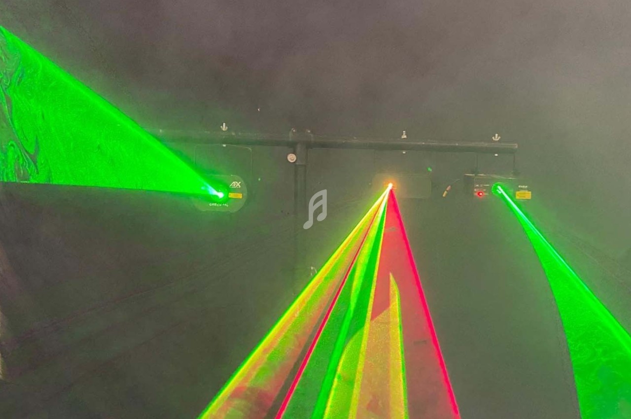 Faisceaux laser verts et rouges projetés dans une atmosphère enfumée, créant un effet lumineux vibrant.