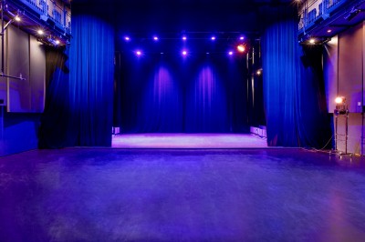 Salle lumineuse avec parquet, grandes baies vitrées donnant sur une rue urbaine, et comptoirs blancs alignés.