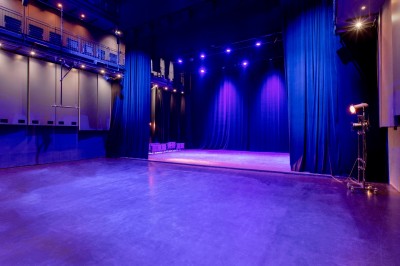 Salle lumineuse avec parquet, grandes baies vitrées donnant sur une rue urbaine, et comptoirs blancs alignés.