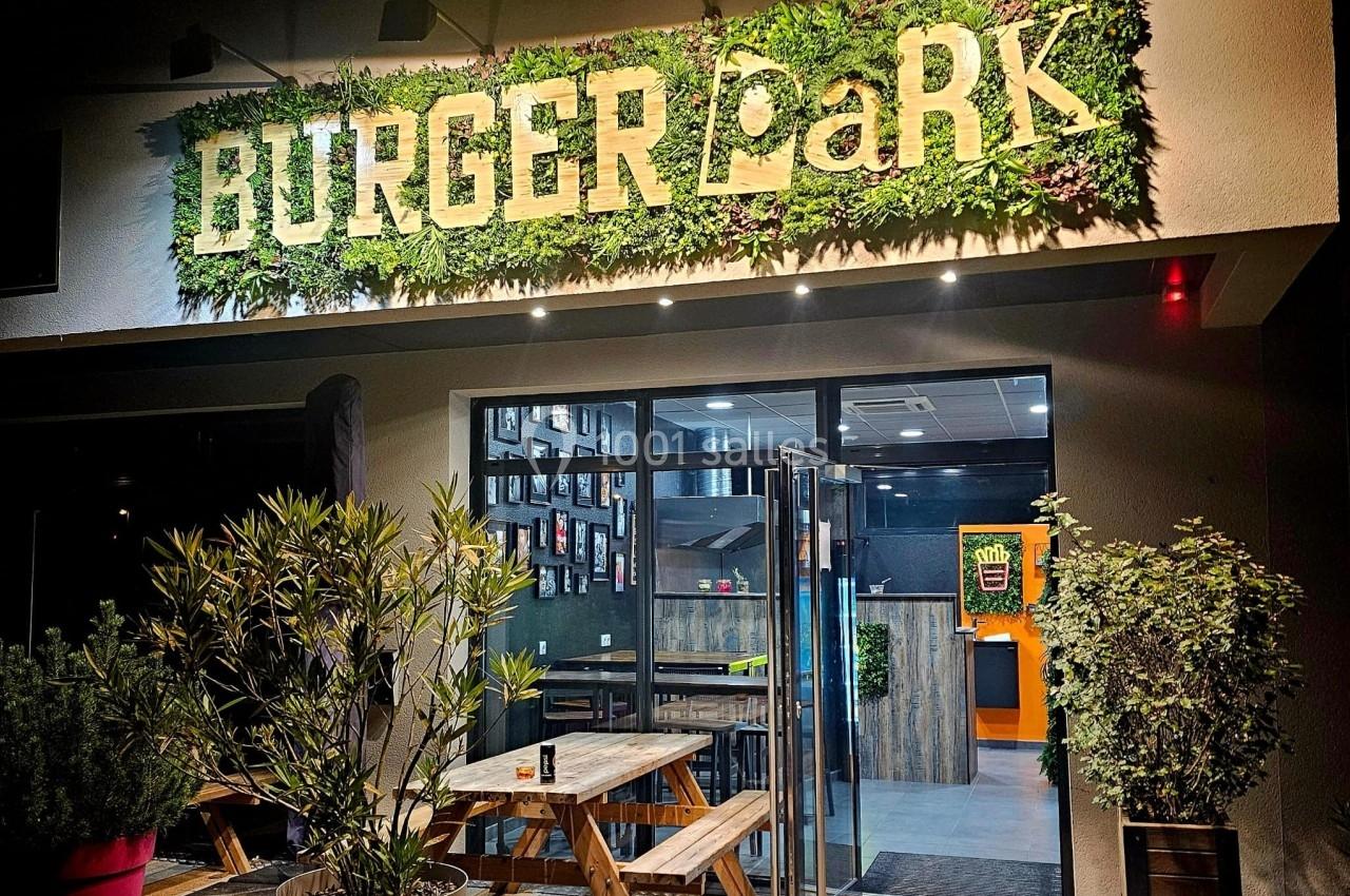 Façade d'un restaurant avec enseigne ’Burger Park’, terrasse en bois et décoration végétale.