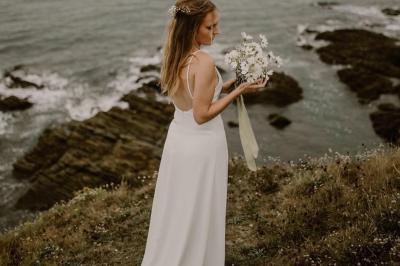 Un couple monte des marches, la mariée en robe blanche et voile, entourée d'invités élégamment vêtus.