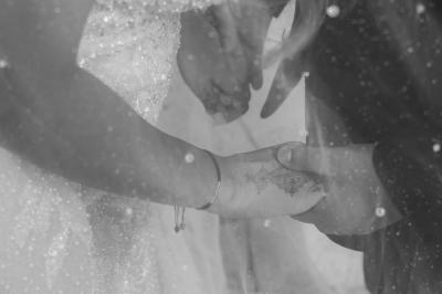 Un couple monte des marches, la mariée en robe blanche et voile, entourée d'invités élégamment vêtus.