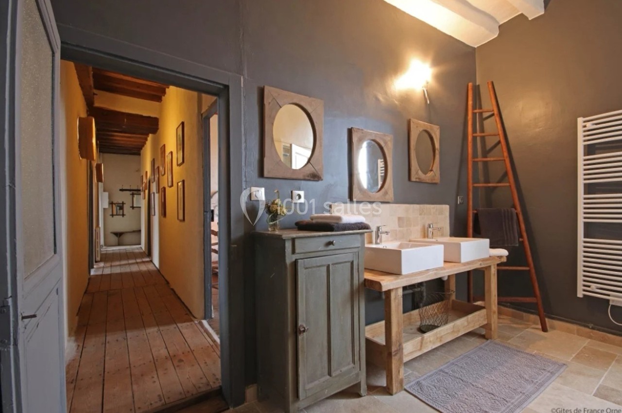 Salle de bain avec murs gris, double vasque sur meuble en bois, échelle porte-serviettes et miroir rond.