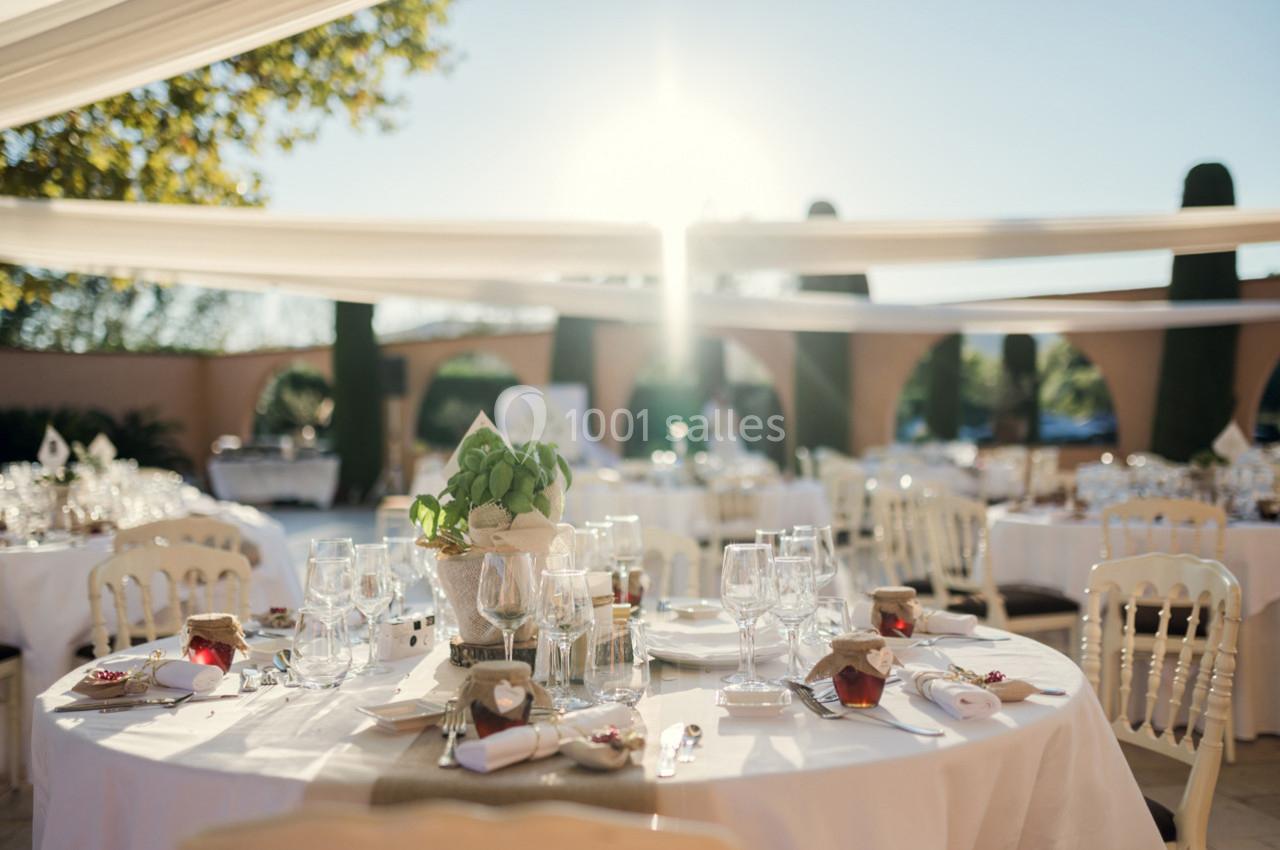 Tables élégamment dressées en extérieur, décorées de fleurs et de vaisselle, sous une lumière naturelle au coucher du soleil.