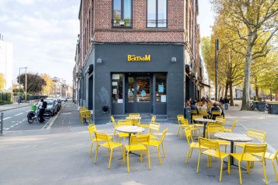 Un couteau et un saucisson sec posé sur une planche en bois, avec un verre de bière en arrière-plan.