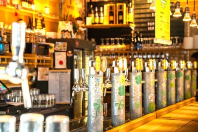 Un couteau et un saucisson sec posé sur une planche en bois, avec un verre de bière en arrière-plan.