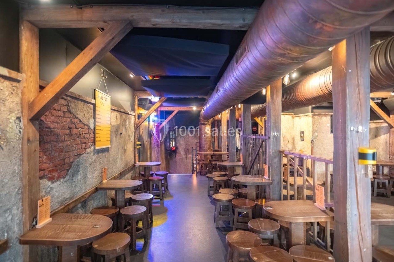Salle intérieure d'un bar ou restaurant avec des tables en bois, des murs en pierre et une ambiance rustique.