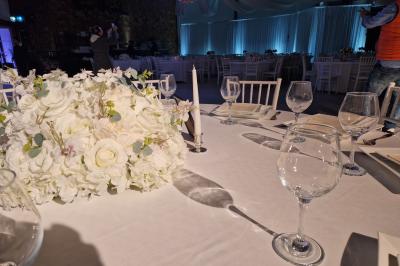 Salle moderne avec tables hautes blanches, éclairage coloré et murs vitrés, prête pour un événement.