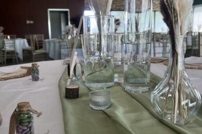 Salle moderne avec tables hautes blanches, éclairage coloré et murs vitrés, prête pour un événement.