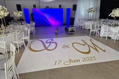 Salle moderne avec tables hautes blanches, éclairage coloré et murs vitrés, prête pour un événement.