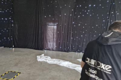 Salle moderne avec tables hautes blanches, éclairage coloré et murs vitrés, prête pour un événement.