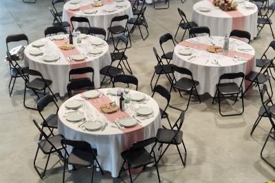Salle moderne avec tables hautes blanches, éclairage coloré et murs vitrés, prête pour un événement.