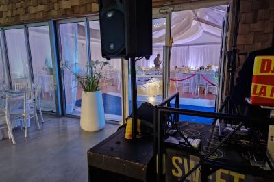 Salle moderne avec tables hautes blanches, éclairage coloré et murs vitrés, prête pour un événement.