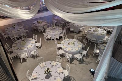 Salle moderne avec tables hautes blanches, éclairage coloré et murs vitrés, prête pour un événement.