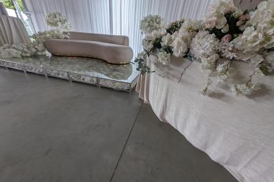 Salle moderne avec tables hautes blanches, éclairage coloré et murs vitrés, prête pour un événement.