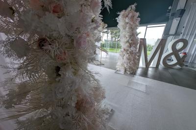 Salle moderne avec tables hautes blanches, éclairage coloré et murs vitrés, prête pour un événement.