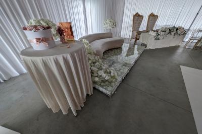 Salle moderne avec tables hautes blanches, éclairage coloré et murs vitrés, prête pour un événement.