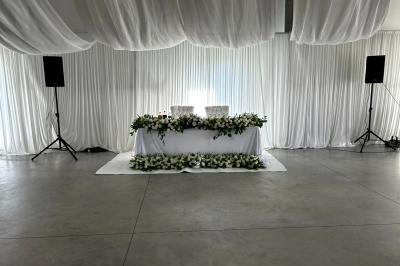 Salle moderne avec tables hautes blanches, éclairage coloré et murs vitrés, prête pour un événement.