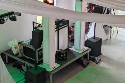 Salle moderne avec tables hautes blanches, éclairage coloré et murs vitrés, prête pour un événement.