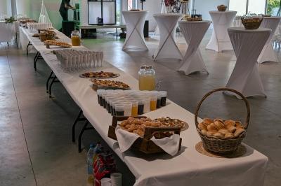 Salle moderne avec tables hautes blanches, éclairage coloré et murs vitrés, prête pour un événement.