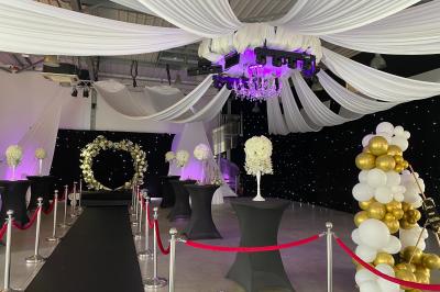 Salle moderne avec tables hautes blanches, éclairage coloré et murs vitrés, prête pour un événement.