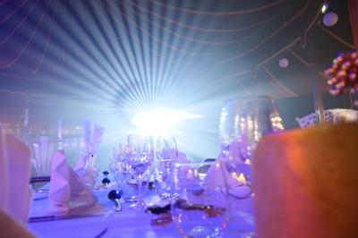 Salle moderne avec tables hautes blanches, éclairage coloré et murs vitrés, prête pour un événement.