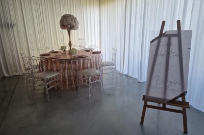 Salle moderne avec tables hautes blanches, éclairage coloré et murs vitrés, prête pour un événement.