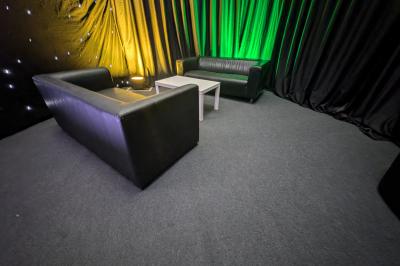 Salle moderne avec tables hautes blanches, éclairage coloré et murs vitrés, prête pour un événement.