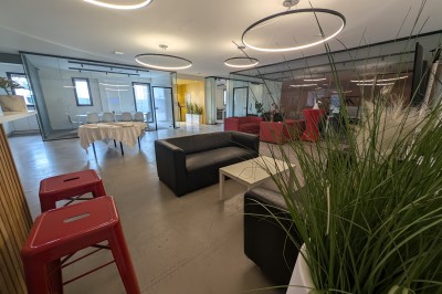 Salle moderne avec tables hautes blanches, éclairage coloré et murs vitrés, prête pour un événement.