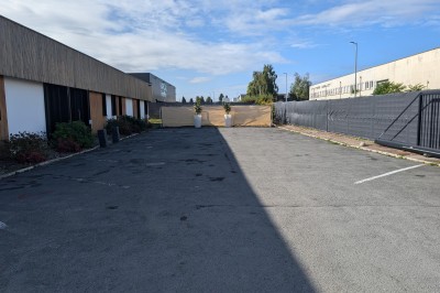 Salle moderne avec tables hautes blanches, éclairage coloré et murs vitrés, prête pour un événement.