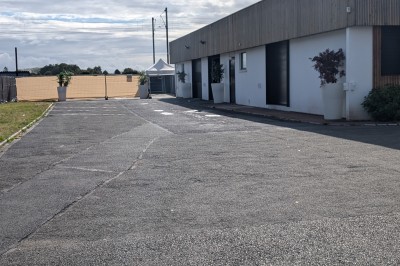 Salle moderne avec tables hautes blanches, éclairage coloré et murs vitrés, prête pour un événement.