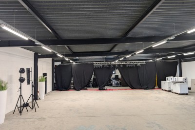 Salle moderne avec tables hautes blanches, éclairage coloré et murs vitrés, prête pour un événement.