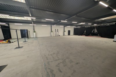 Salle moderne avec tables hautes blanches, éclairage coloré et murs vitrés, prête pour un événement.